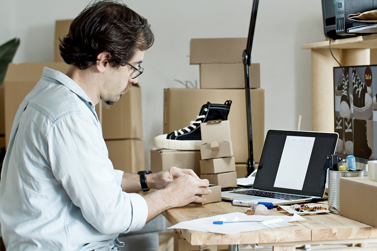 about-us-02 Businessman packing products and managing an online store from his desk with a laptop.